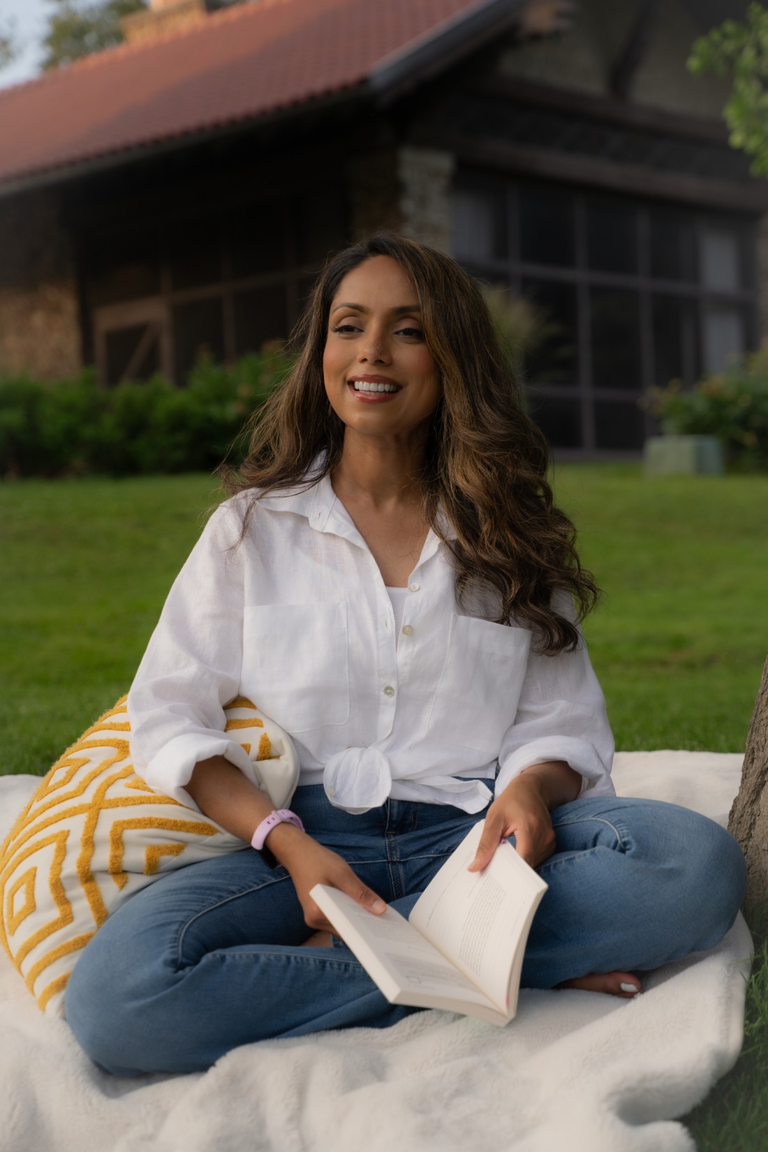 Ferdous, founder of Aligned Myndset, sitting relaxed outdoors with a book, smiling warmly