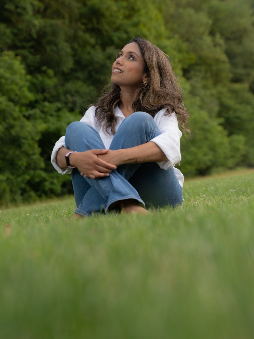 Ferdous sitting on the grass in an open meadow, looking up and away