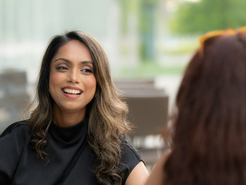 Ferdous smiling warmly across a table during a coaching conversation with a client